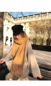 Street style shot of thick camel mohair scarf with large tassels and grey knit sweater