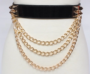 Detail of black patent leather belt featuring triple layered gold metal chains and punk studs