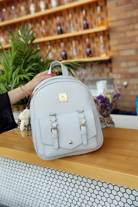 Nahaufnahme der hellgrauen PU-Leder Rucksack mit Blumenschnalle und Plüsch-Anhänger