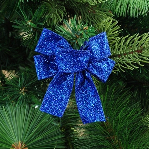 Detail of 10cm sparkling blue glitter Christmas bow ornament hanging on a green tree branch