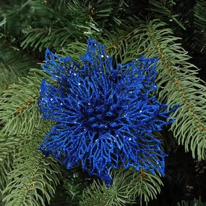 Detail of blue glitter Christmas flower ornament on a green pine tree branch