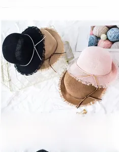 Detailed macro view of woven raffia sun hats featuring fringe brims and decorative bows