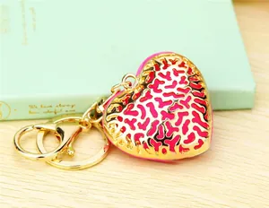Close-up of pink enamel heart keychain with gold coral-patterned cutout overlay and lobster clasp