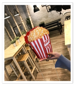 Detail of red and white striped popcorn shape crossbody bag with gold chain strap