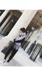 Close-up of a light grey thick mohair scarf with tassels on a model in urban setting