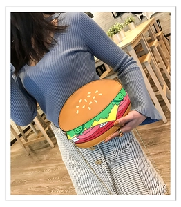 Funny hamburger shaped crossbody bag with chain strap shown in a cozy cafe setting