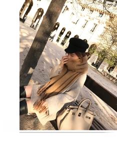 Close-up of camel mohair scarf with tassels paired with a grey knit sweater and boots