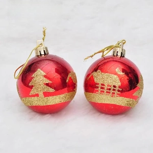 Detail of red Christmas baubles with golden pine tree patterns on white faux fur