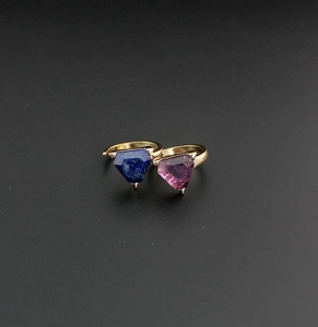 Detail of minimalist gold rings featuring triangular lapis lazuli and amethyst gemstones