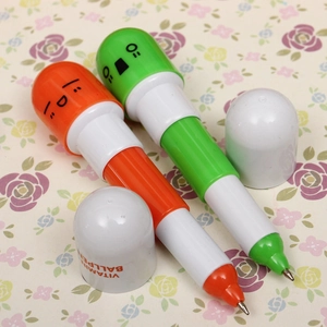 Macro shot of two creative capsule pens in orange and green with cute cartoon faces