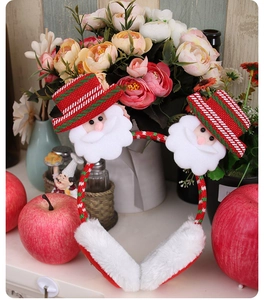 Detail view of plush red Christmas earmuffs with Santa Claus and festive striped hat decor