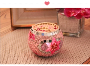 Pink mosaic glass candle holder with star and moon patterns on a woven mat in cozy setting