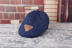 Close-up of navy blue striped beret cap with a brown leather bear patch on lace fabric
