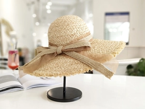 Detail eines Raffia-Strohhuts mit elegantem Schleifenknoten und gefranstem Randdesign