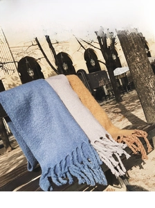 Detail of soft mohair scarves in blue, grey, and caramel with long fringe tassels