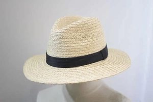 Detailed close-up of woven raffia sun hat texture with black ribbon on a mannequin head