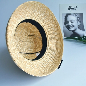 Detail view of the interior straw weave texture with black sweatband and chin strap