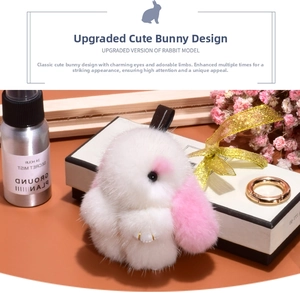 Detailed close-up of a plush pink and white rabbit charm with golden hardware