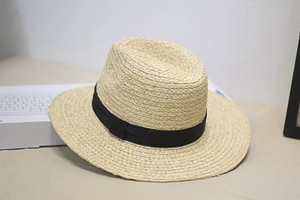 Close-up of finely woven raffia sun hat featuring a classic black decorative ribbon