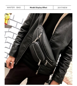 Detail view of a black multi-zippered chest bag with shiny metal hardware on model