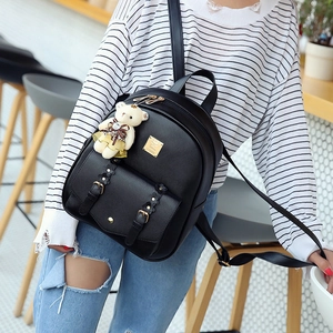 Detailansicht eines schwarzen Kunstleder-Rucksacks mit goldenen Beschlägen und Bärenanhänger