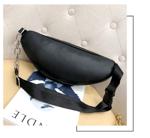 Detail of a crescent black leather fanny pack with wide strap and metal chain detail