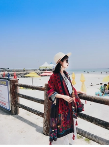 Detail of red Bohemian shawl with mandala patterns and fringe trim for beach vacations