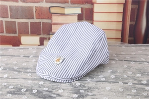 Detail of baby striped beret featuring blue and white stripes and a metallic anchor badge