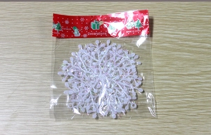 Detail view of white Christmas snowflake decorations in retail packaging on wood surface