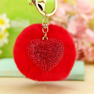 Close-up of fluffy red pompom keychain with a sparkling rhinestone heart pendant
