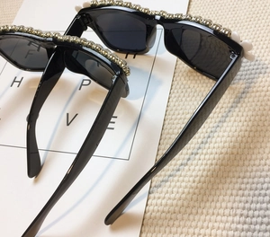 Detailed top view of black round sunglasses featuring gold floral rhinestones and pearls