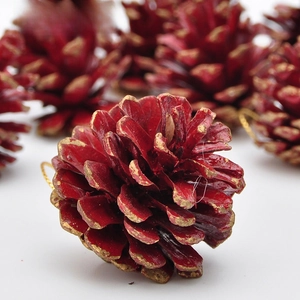 Dettaglio di pigne natalizie rosse con bordi glitterati dorati e cordino d'oro per appenderle