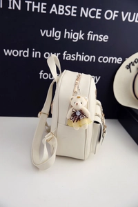 Details des weißen PU-Rucksacks mit goldenen Metallteilen und Bären-Anhänger-Zubehör