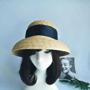 Detail of classic straw cloche hat featuring wide black ribbon on model head