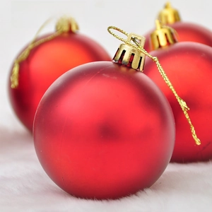 Close-up of matte red shatterproof Christmas baubles on white faux fur background