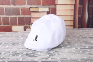 Close-up of a white striped beret with black rabbit embroidery on lace tablecloth