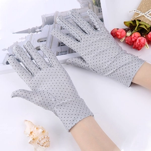 Close-up of grey sun protection gloves with black polka dots and lace texture