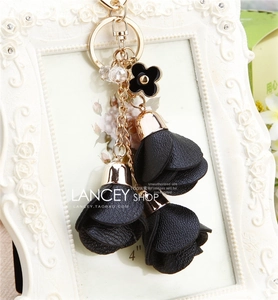 Detail of black leather flower tassel keychain with golden chain and clover charm