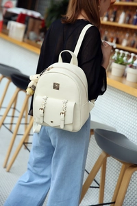 Weißer PU-Lederrucksack mit Blumenschnallen und Bärenanhänger an einem weiblichen Modell