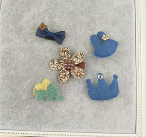 Detail view of 5-piece girls' hair clips set with crown, bow, and elephant designs