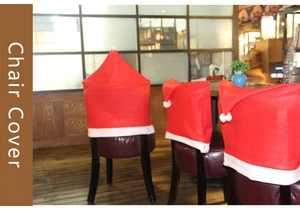 Three red Santa hat chair covers with white fur trim and pom-poms on dining chairs
