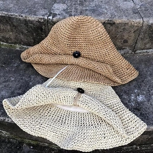 Detailed view of handmade woven straw sun hats with buckle ties and decorative buttons