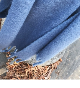 Detail view showing soft blue mohair texture and delicate tassels on the knit scarf