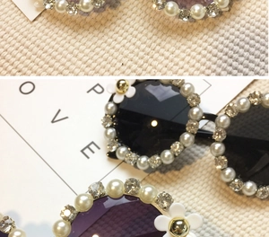 Close-up of floral sunglasses with white daisies, pearls and rhinestones on purple lenses
