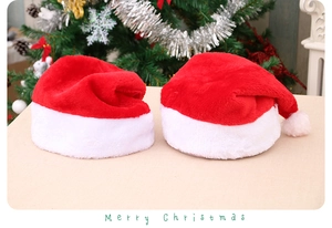 Two plush red and white Christmas hats on a festive background with Merry Christmas text