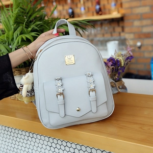 Detail eines hellgrauen PU-Rucksacks mit floralen Riemen und goldener Logoplakette