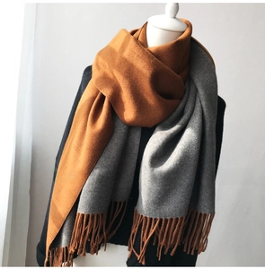 Detail of soft double-sided scarf showing fringe texture in caramel and grey colors