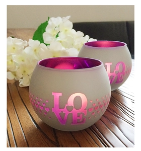 Detail of two frosted purple glass candle holders with LOVE and heart cut-outs