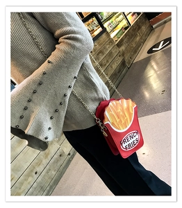 Creative red french fries crossbody bag with metal chain strap worn by a model in a mall