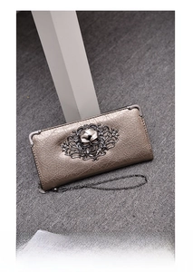 Detail of vintage punk long wallet with bronze skull relief and cracked texture